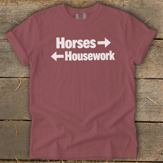 A mauve t-shirt with white text reading "Horses" pointing right and "Housework" pointing left.