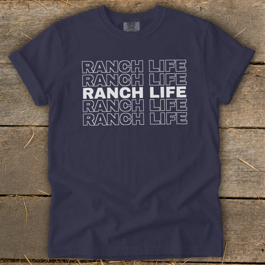 Navy blue crewneck t-shirt featuring stacked white outline text reading RANCH LIFE on a wooden surface.