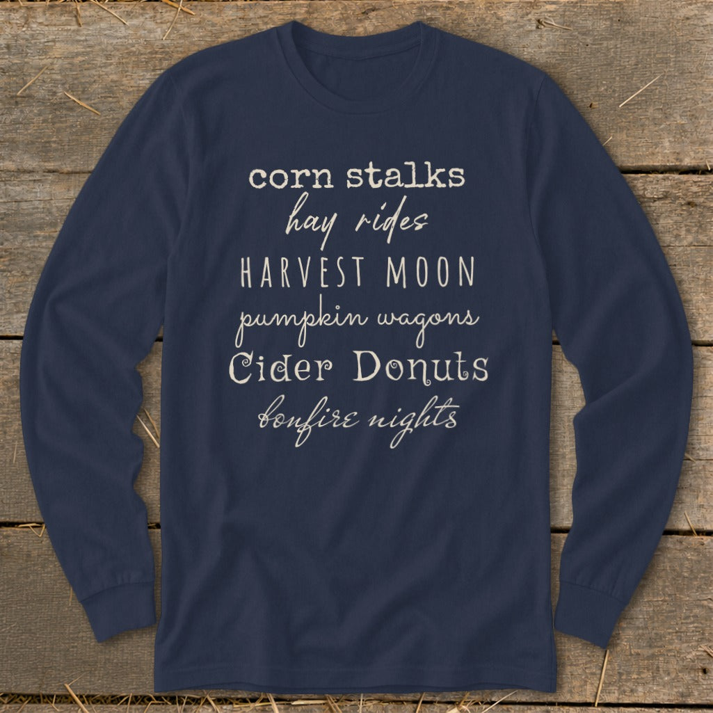 Navy long sleeve shirt with autumn phrases: corn stalks, hay rides, harvest moon, pumpkin wagons, cider donuts, bonfire nights.