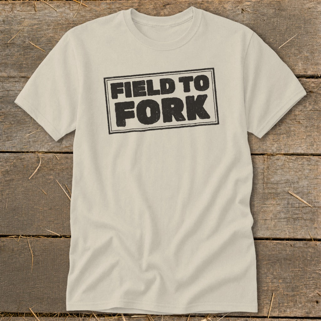 A cream-colored short-sleeved t-shirt with the words "FIELD TO FORK" printed in black on the chest.