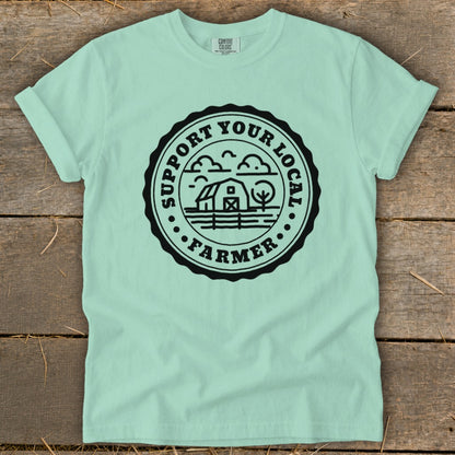 Mint t-shirt with black circular graphic reading "Support Your Local Farmer" and farm scene.