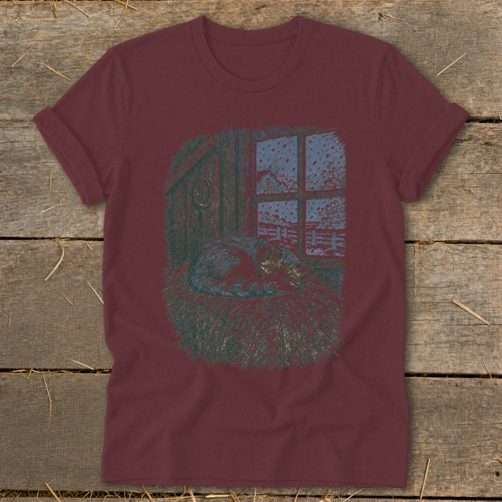 T-shirt with illustration of a cat sleeping in hay by a window.