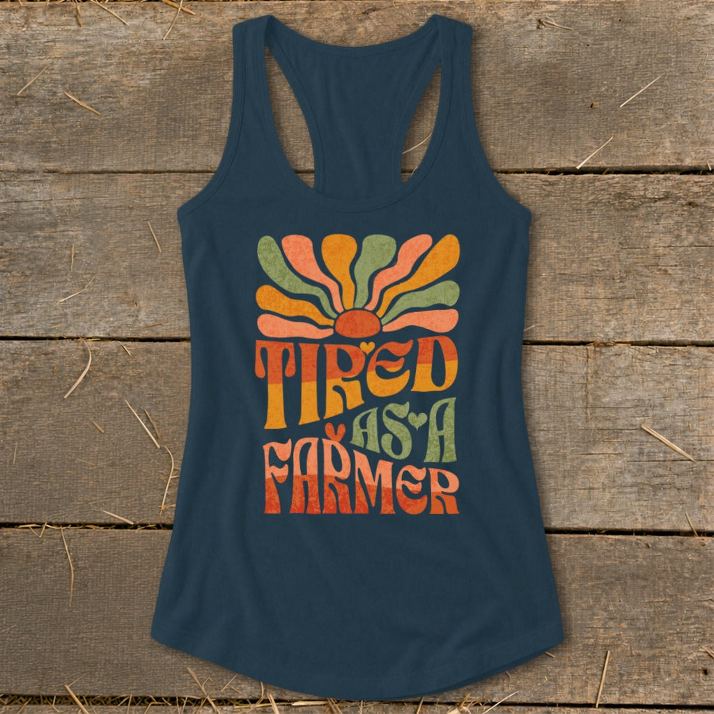 Navy tank top with "Tired As A Farmer" text and retro sun graphic.
