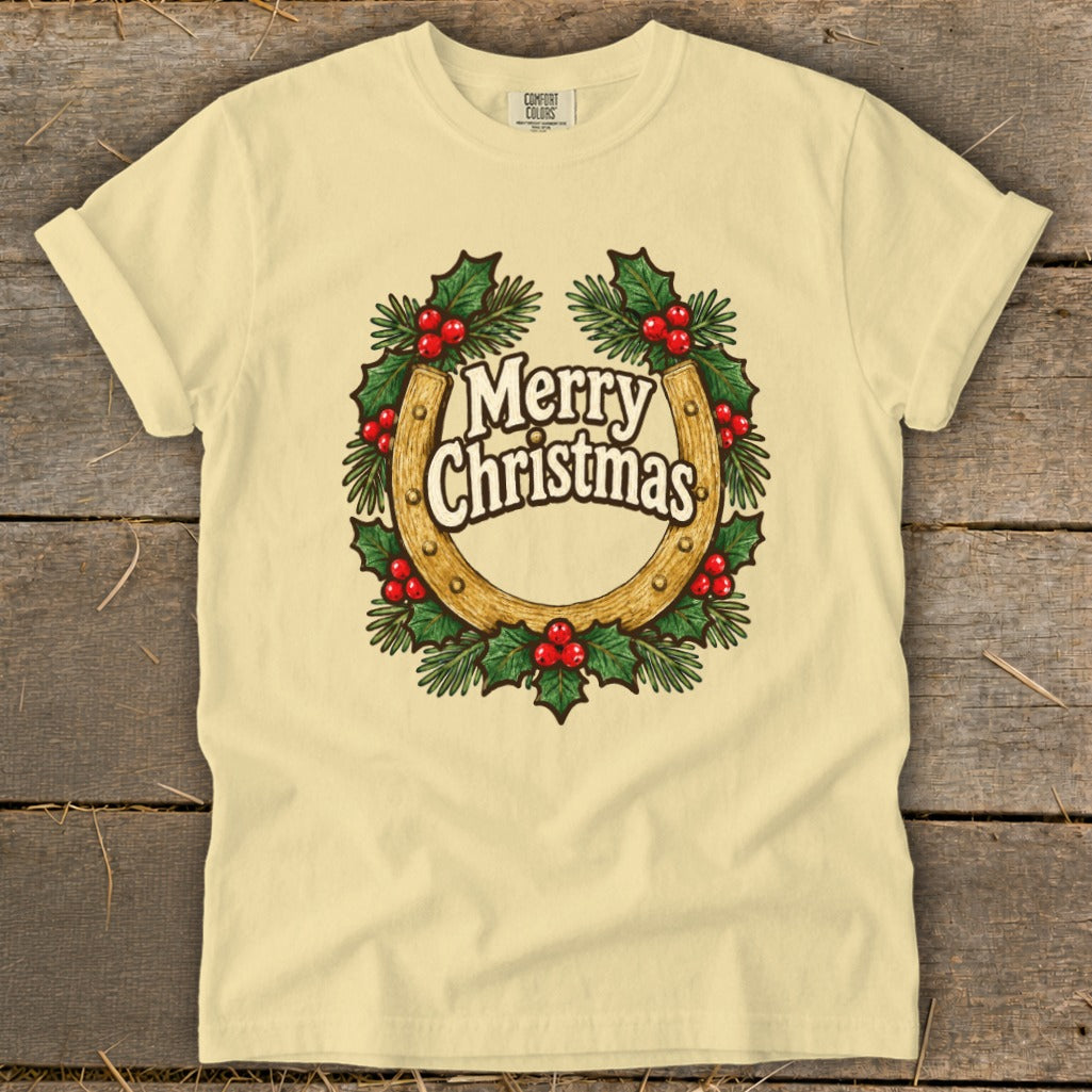 Pale yellow t-shirt with a horseshoe Christmas wreath graphic that says "Merry Christmas".