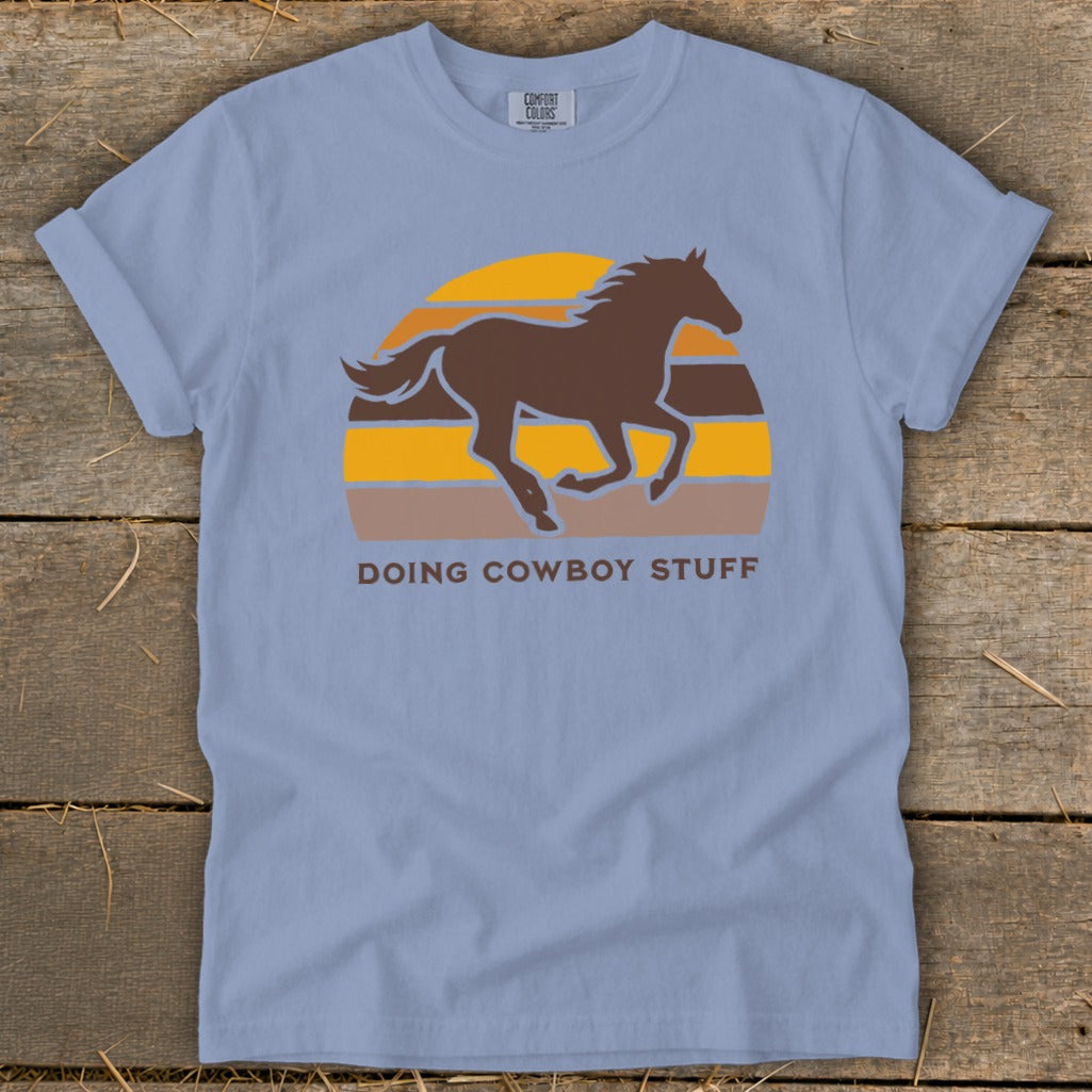 Light blue t-shirt with a running horse graphic and "Doing Cowboy Stuff" text.