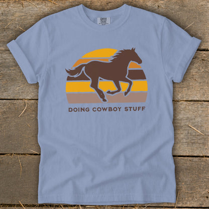Light blue t-shirt with a running horse graphic and "Doing Cowboy Stuff" text.