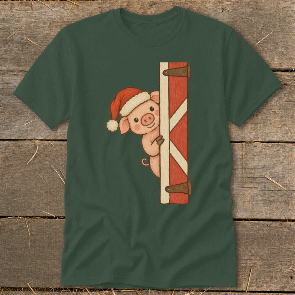 Green t-shirt with a cartoon pig wearing a Santa hat peeking around a red barn door.