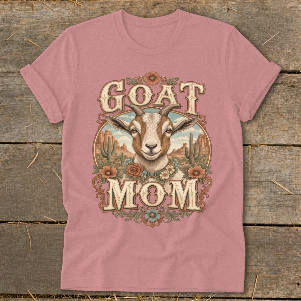 Goat Mom graphic with a goat head and desert scenery on a pastel pink t-shirt.