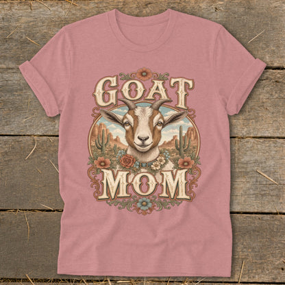 Goat Mom graphic with a goat head and desert scenery on a pastel pink t-shirt.