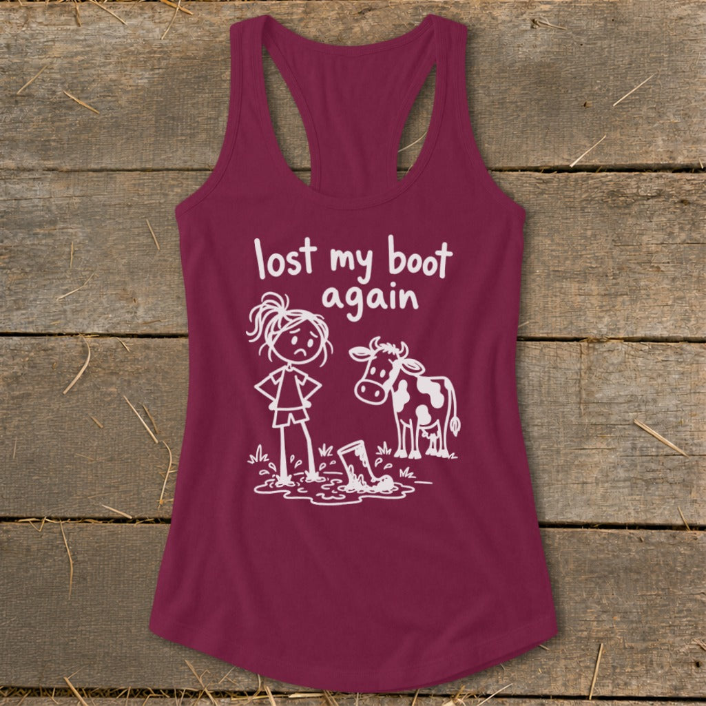 Maroon women's racerback tank top featuring a white graphic of a cow and a sad girl standing in mud beside a lost boot, with the text "lost my boot again."