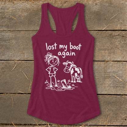 Maroon women's racerback tank top featuring a white graphic of a cow and a sad girl standing in mud beside a lost boot, with the text "lost my boot again."