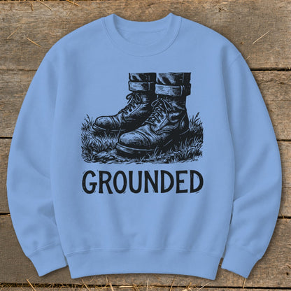 Light blue sweatshirt with "GROUNDED" text and sketch of boots in grass.