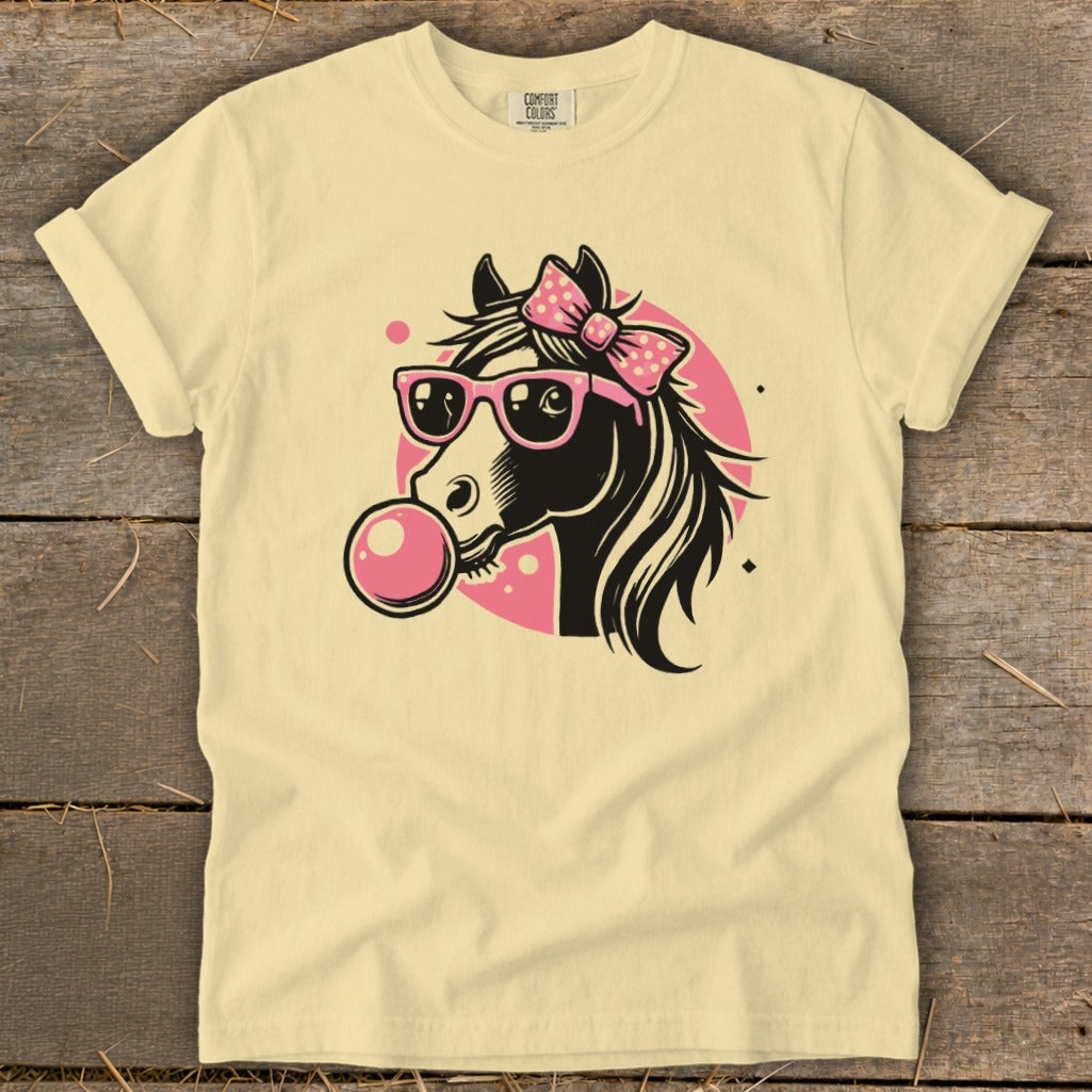 Yellow t-shirt with a black horse head wearing pink sunglasses and blowing a pink bubble gum bubble.