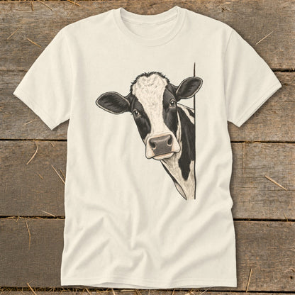 Black and white cow peeking from the side on a cream t-shirt.