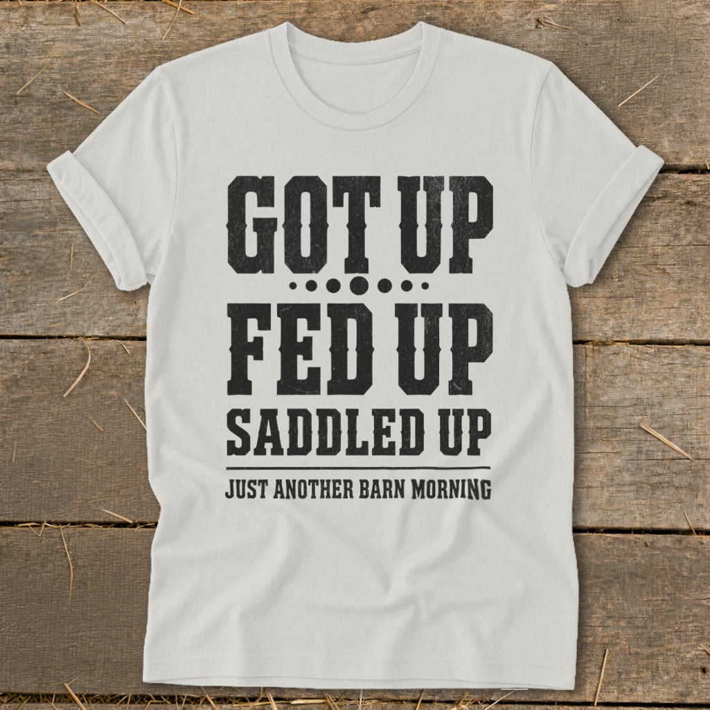 White t-shirt with black text reading "GOT UP FED UP SADDLED UP JUST ANOTHER BARN MORNING".