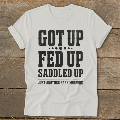 White t-shirt with black text reading "GOT UP FED UP SADDLED UP JUST ANOTHER BARN MORNING".