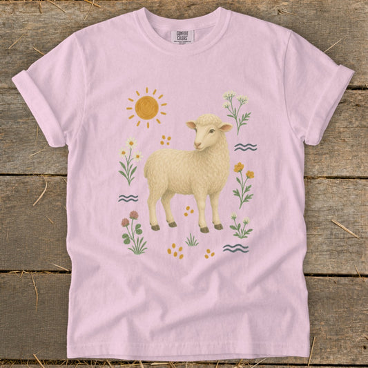 Pink t-shirt with a cream sheep graphic surrounded by sun, flowers, and wavy lines.