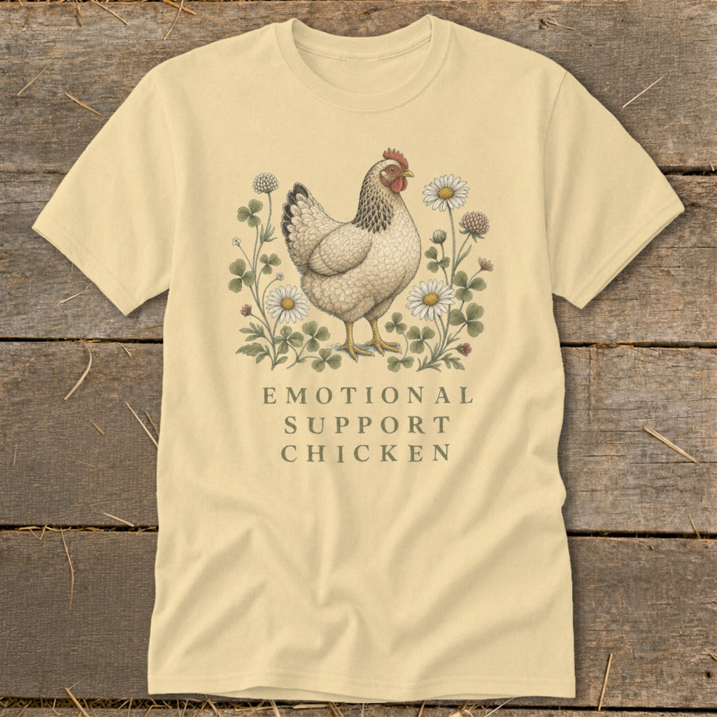 Pale yellow t-shirt with an illustration of a chicken among flowers and text "EMOTIONAL SUPPORT CHICKEN".