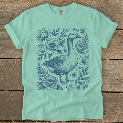 Mint green t-shirt with a blue goose and floral sketch design.
