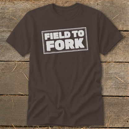 A dark brown crewneck t-shirt featuring the distressed white text FIELD TO FORK inside a rectangular border.