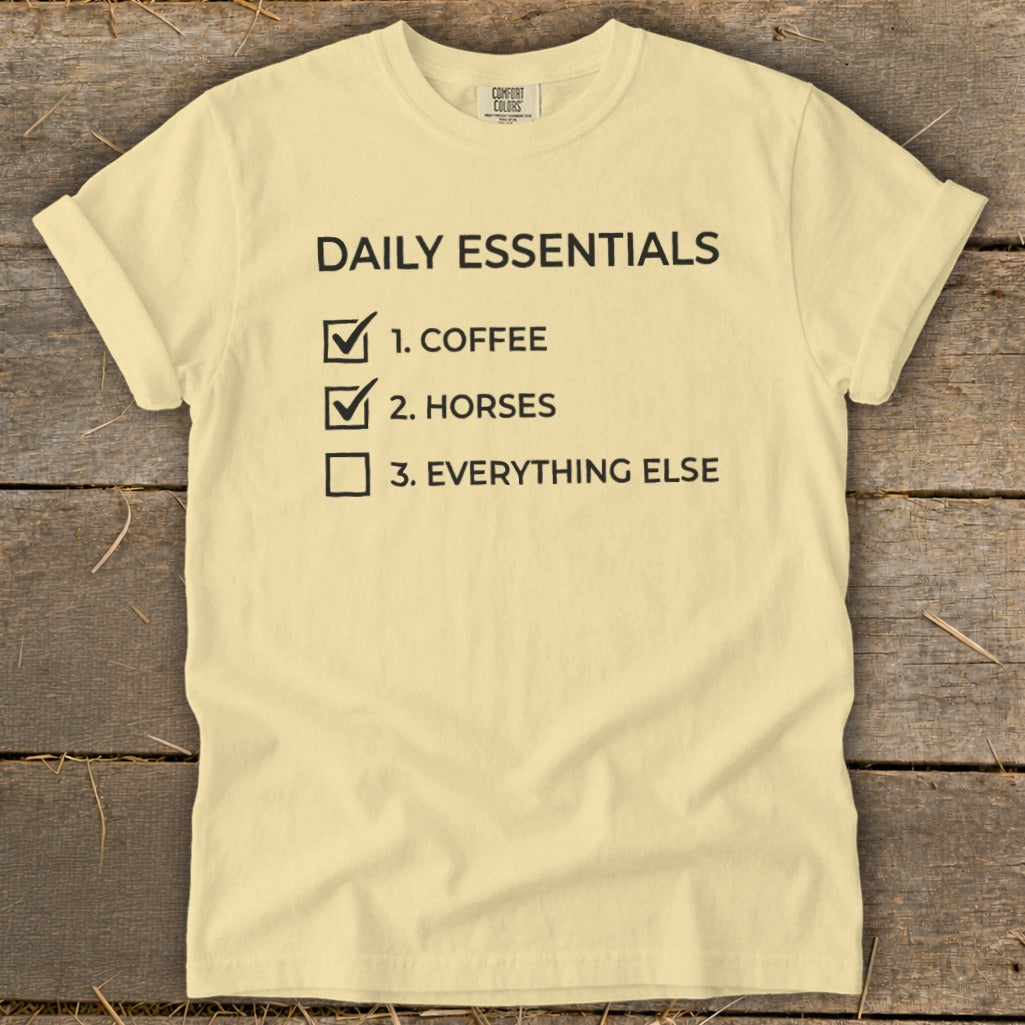 Light yellow t-shirt with "Daily Essentials" checklist: coffee, horses, everything else.