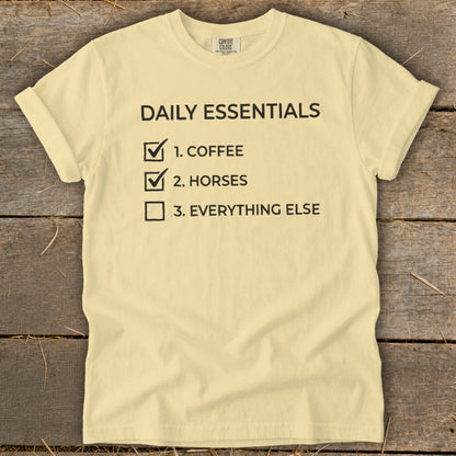 Light yellow t-shirt with "Daily Essentials" checklist: coffee, horses, everything else.