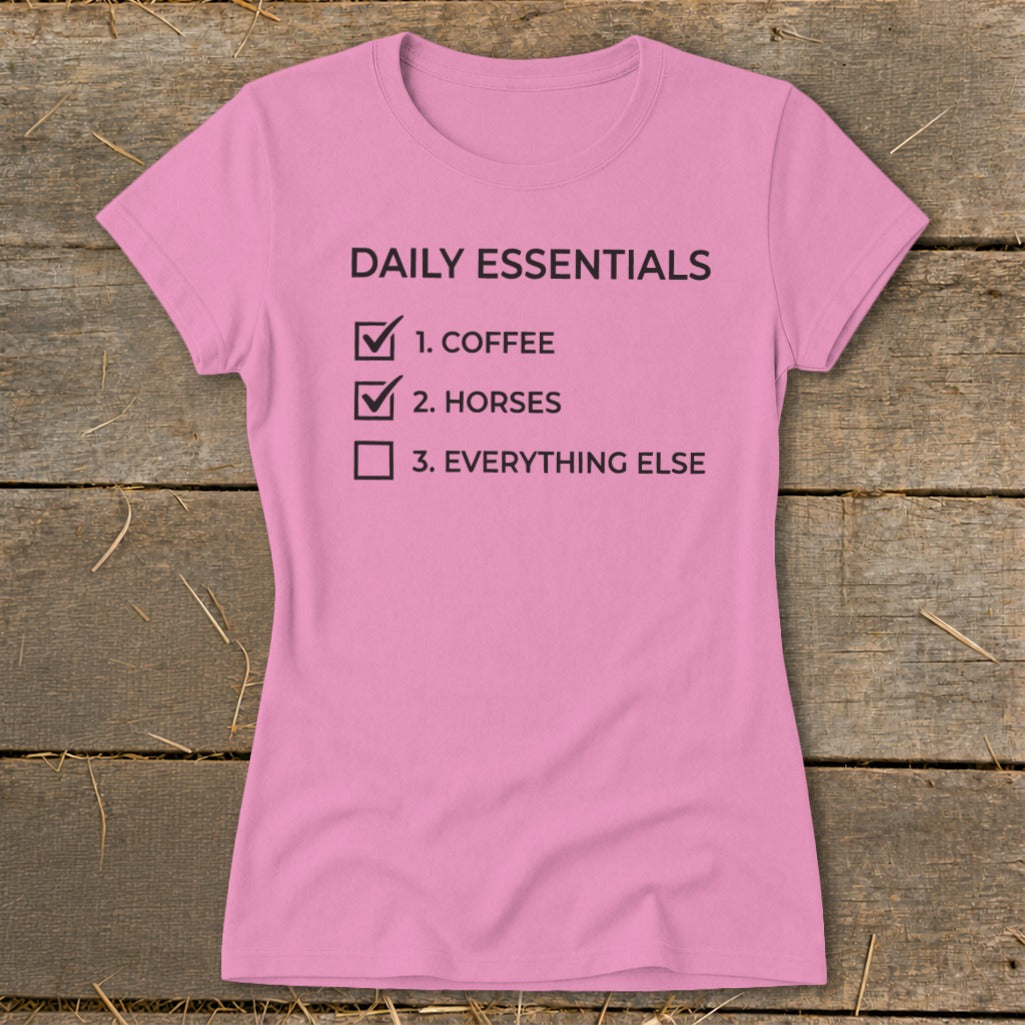 Pink t-shirt with black text listing daily essentials: coffee, horses, and everything else.