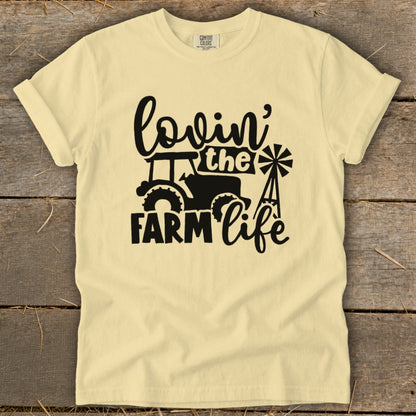 Light yellow t-shirt with black graphic that says "lovin' the FARM life" and shows a tractor and windmill.