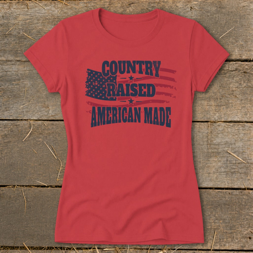 Red t-shirt with navy blue text "Country Raised American Made" and distressed American flag graphic.