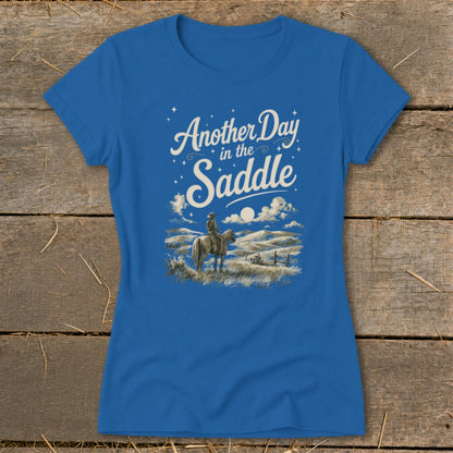 Blue t-shirt with "Another Day in the Saddle" text and cowboy on horse illustration.