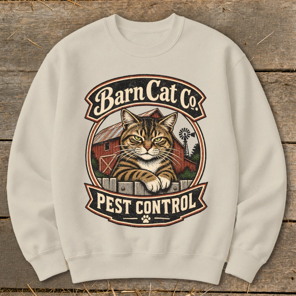 Cream-colored crewneck sweatshirt featuring a graphic of a tabby cat behind a fence with a barn and Barn Cat Co. Pest Control text.