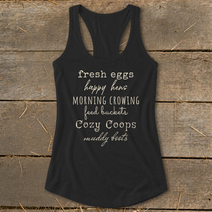 Black tank top with white text: "fresh eggs happy hens MORNING CROWING feed buckets Cozy Coops muddy boots"