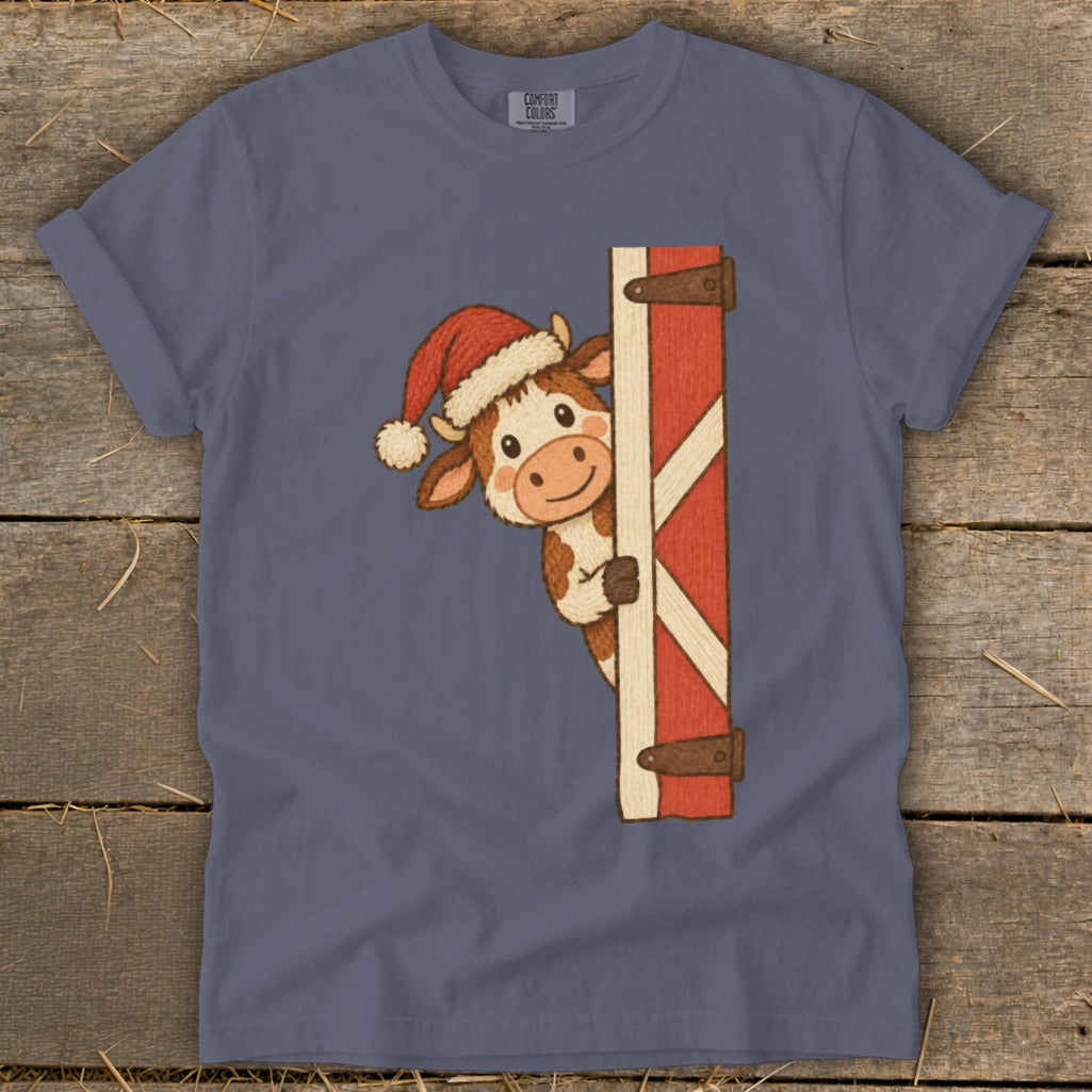 Cartoon cow in Santa hat peeking from behind a red barn door.
