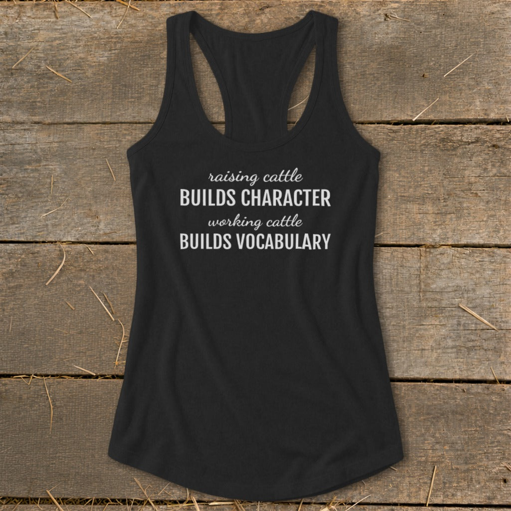 Black tank top with white text: "raising cattle BUILDS CHARACTER working cattle BUILDS VOCABULARY."