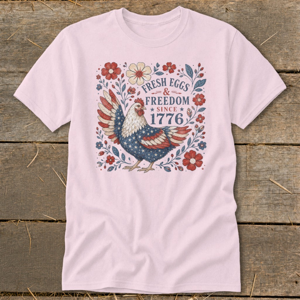 Pink t-shirt with a chicken design featuring "Fresh Eggs & Freedom Since 1776".