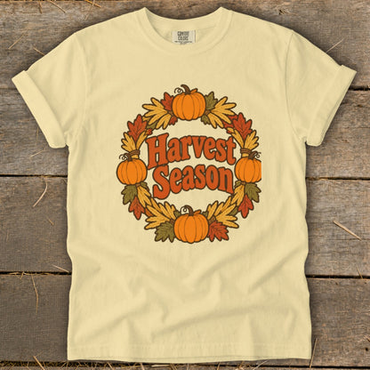 Cream t-shirt with "Harvest Season" text in a circular pumpkin and leaf wreath.