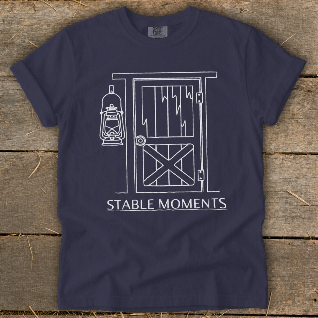 Navy t-shirt with a white line drawing of a barn door and lantern, text reads "STABLE MOMENTS".
