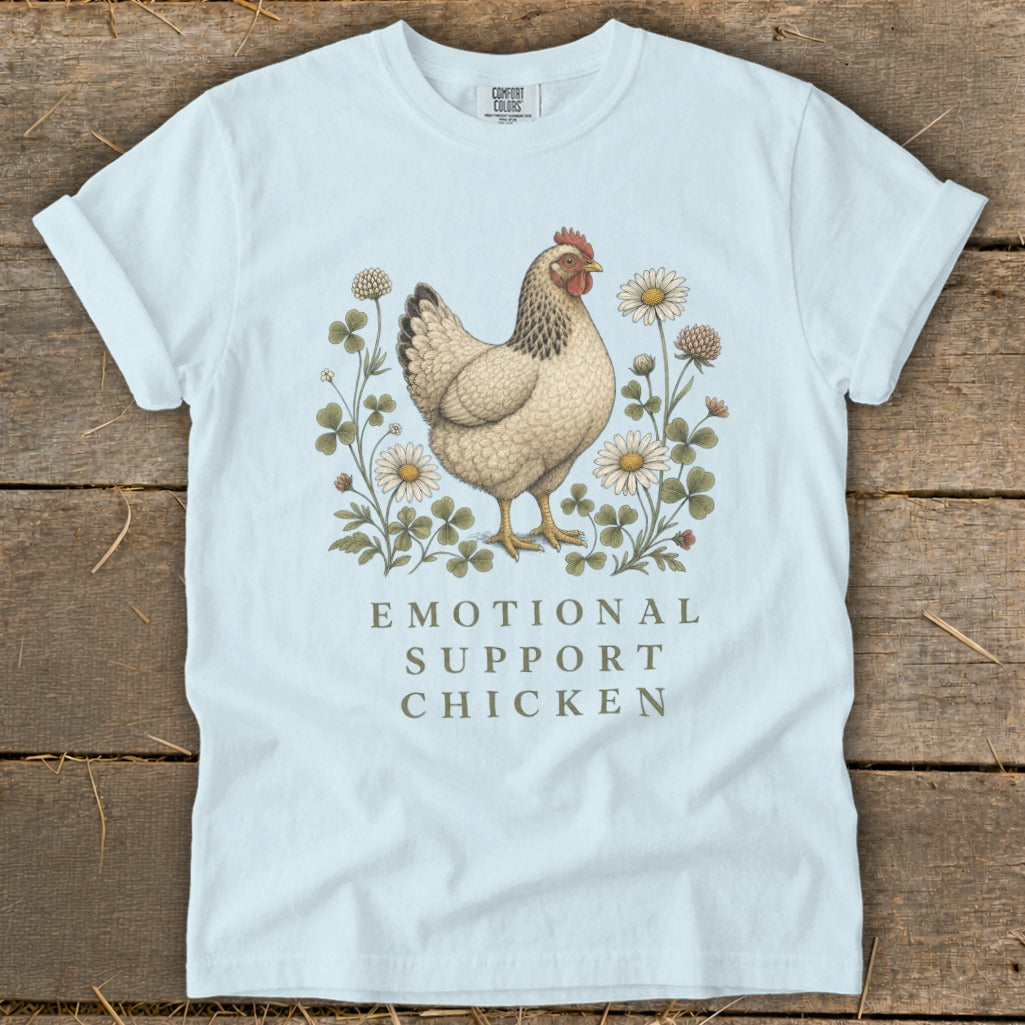 Light blue t-shirt with a hen surrounded by clover and daisies, text reads "Emotional Support Chicken".