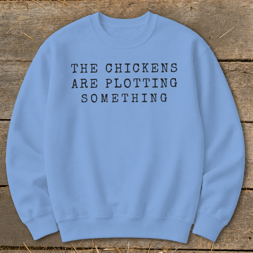 Light blue sweatshirt with "The chickens are plotting something" text.