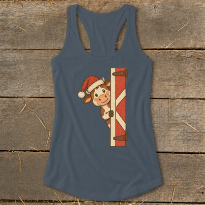 Christmas cow wearing Santa hat peeking around a wooden barn door.