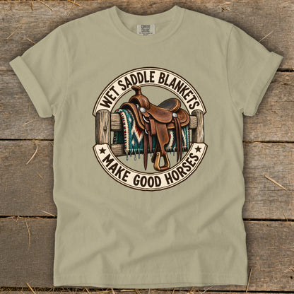 Cowboy saddle on fence with blanket and text "Wet Saddle Blankets Make Good Horses".