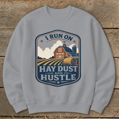 Grey sweatshirt with a farm graphic and the text "I RUN ON HAY DUST AND HUSTLE".