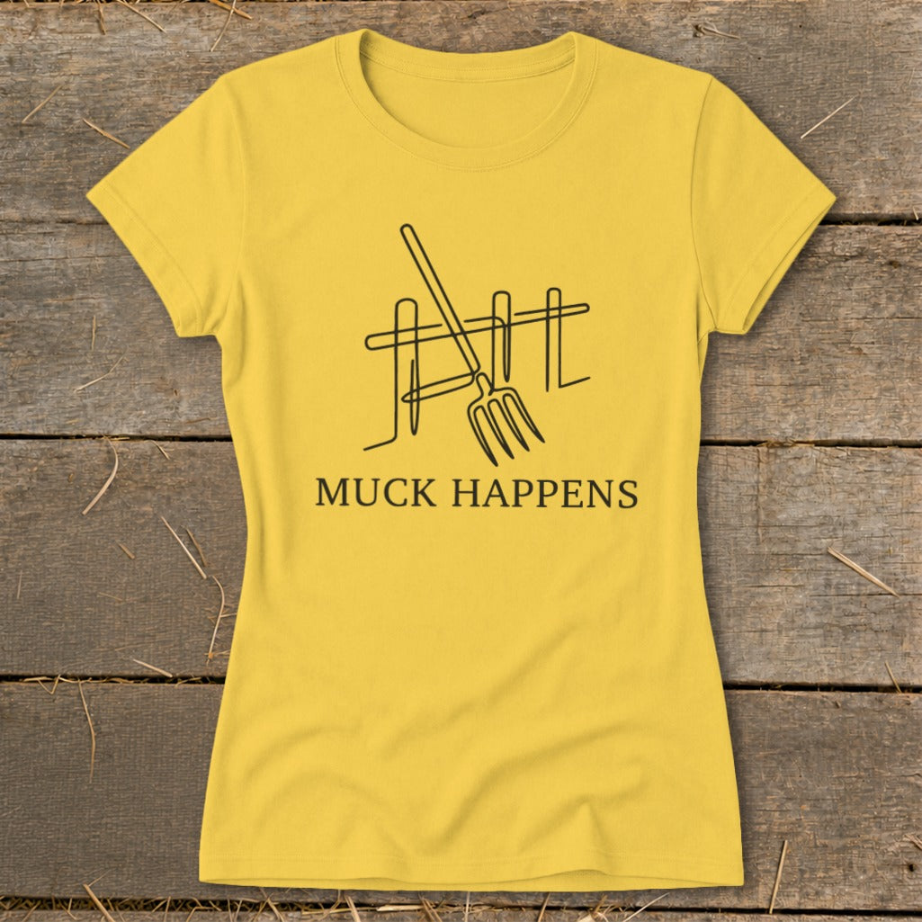 Yellow t-shirt with a black line drawing of a pitchfork and fence, text reads "MUCK HAPPENS".