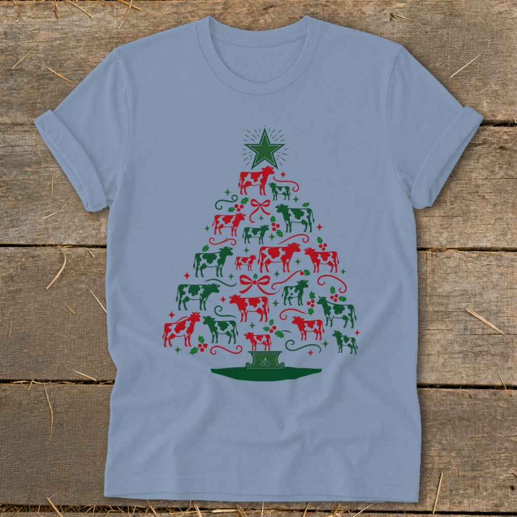 Light blue t-shirt with a Christmas tree made of red and green cows and holly.