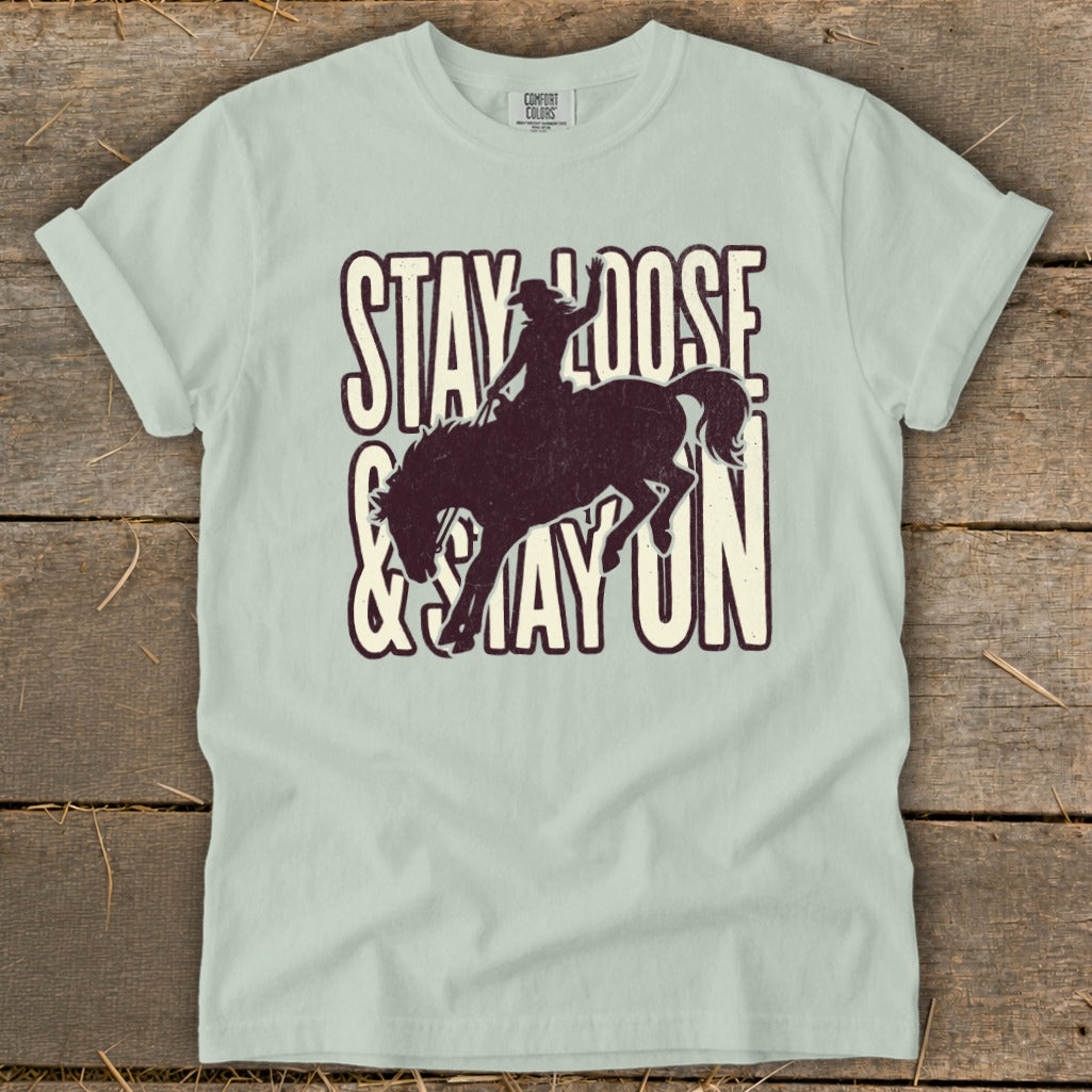 Light blue t-shirt with "STAY LOOSE & STAY ON" text and cowboy silhouette on bucking horse.