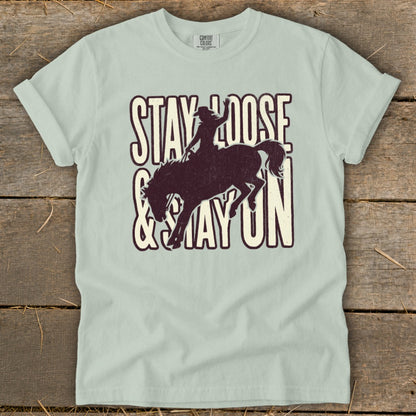 Light blue t-shirt with "STAY LOOSE & STAY ON" text and cowboy silhouette on bucking horse.