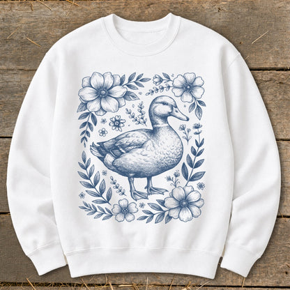 White sweatshirt with a blue line drawing of a duck surrounded by flowers.