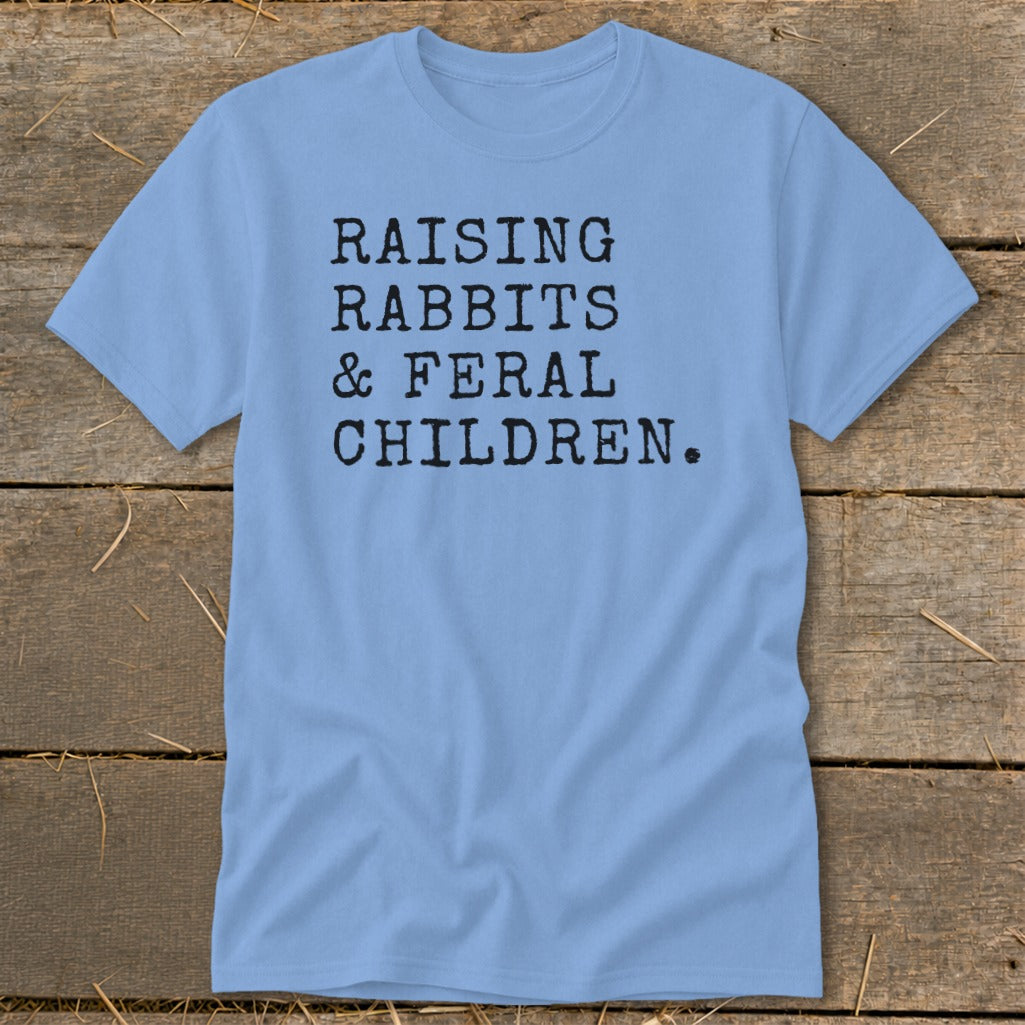 Light blue t-shirt with black text reading "RAISING RABBITS & FERAL CHILDREN."