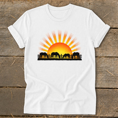White t-shirt with a graphic of horses grazing in front of a rising sun.