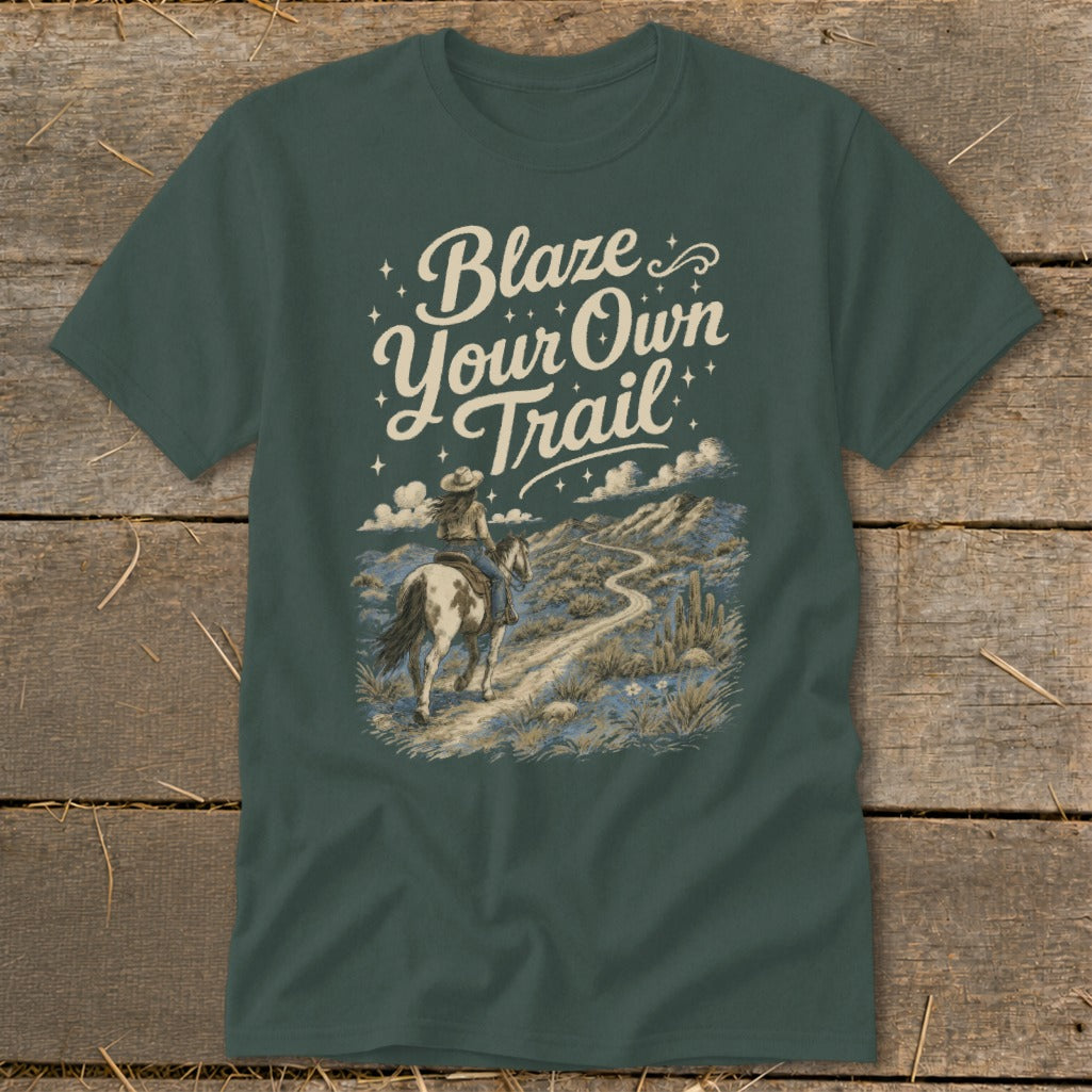 T-shirt graphic with text "Blaze Your Own Trail" and a person riding a horse on a desert path.